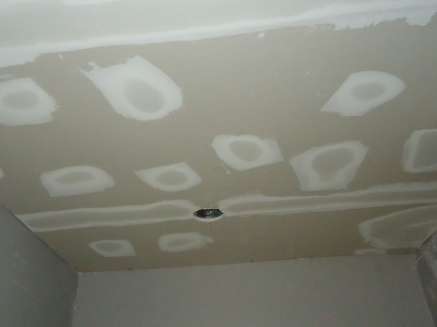 Drywall ceiling with taped seams and screw heads spotted with joint compound